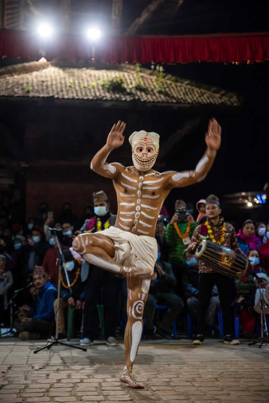 A dancer painted as a skeleton balances on one leg