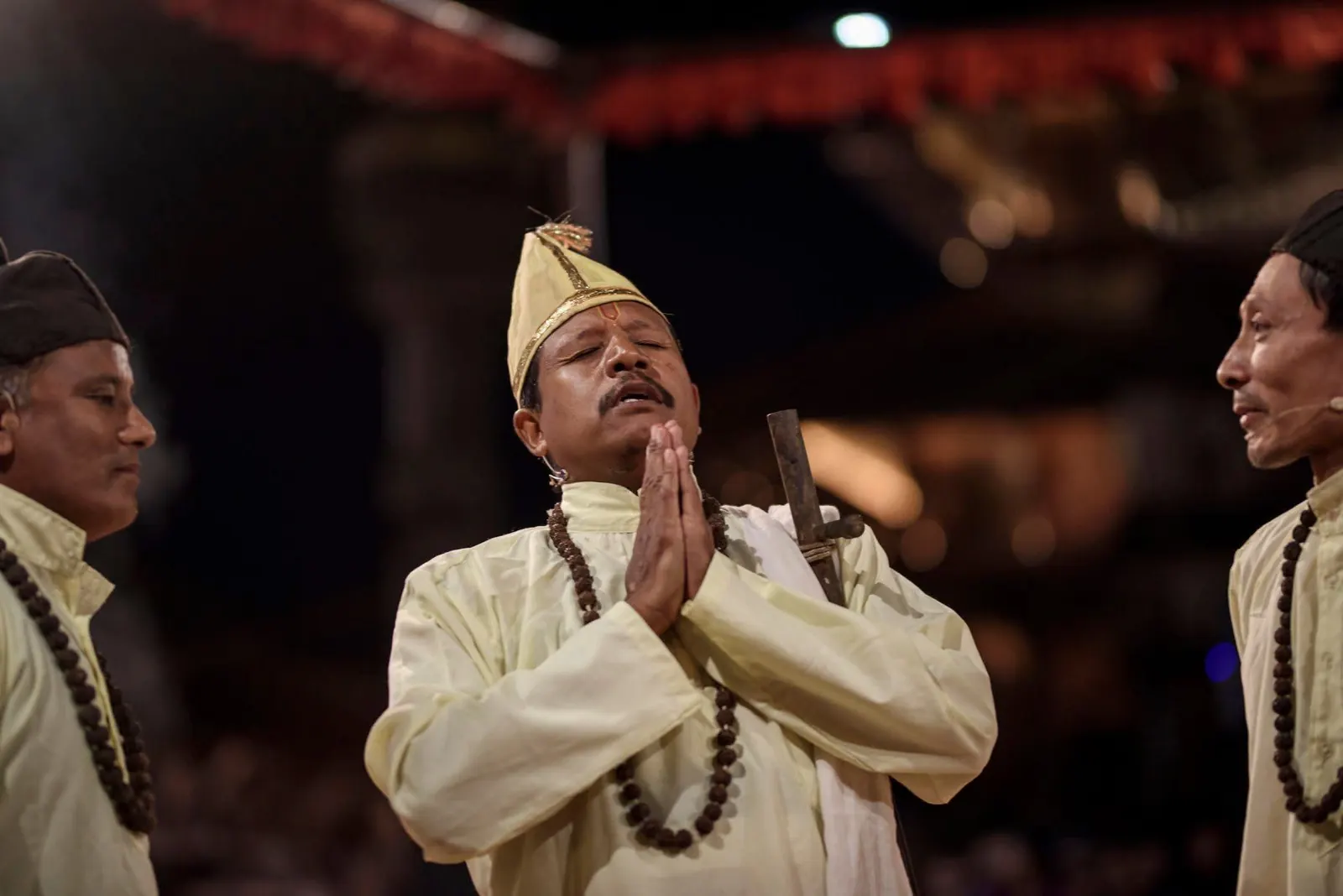 An actor in white joins his palms in prayer